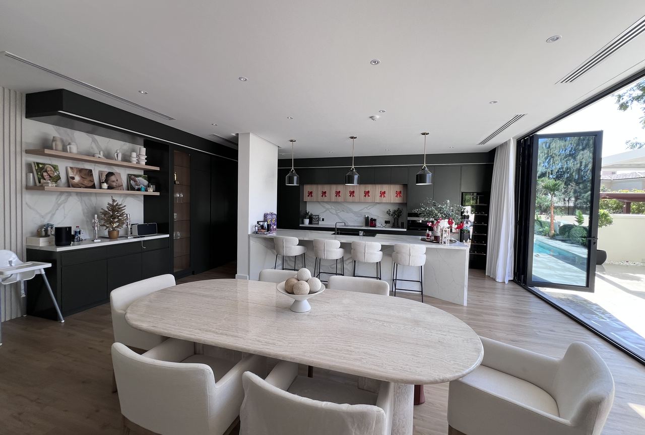 Completed open-plan dining and kitchen in a Dubai villa, with doors open to the pool